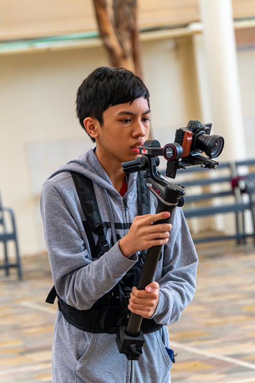 A young man holding a camera and holding a tripod