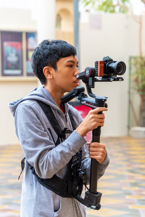 A young man holding a camera and holding a tripod