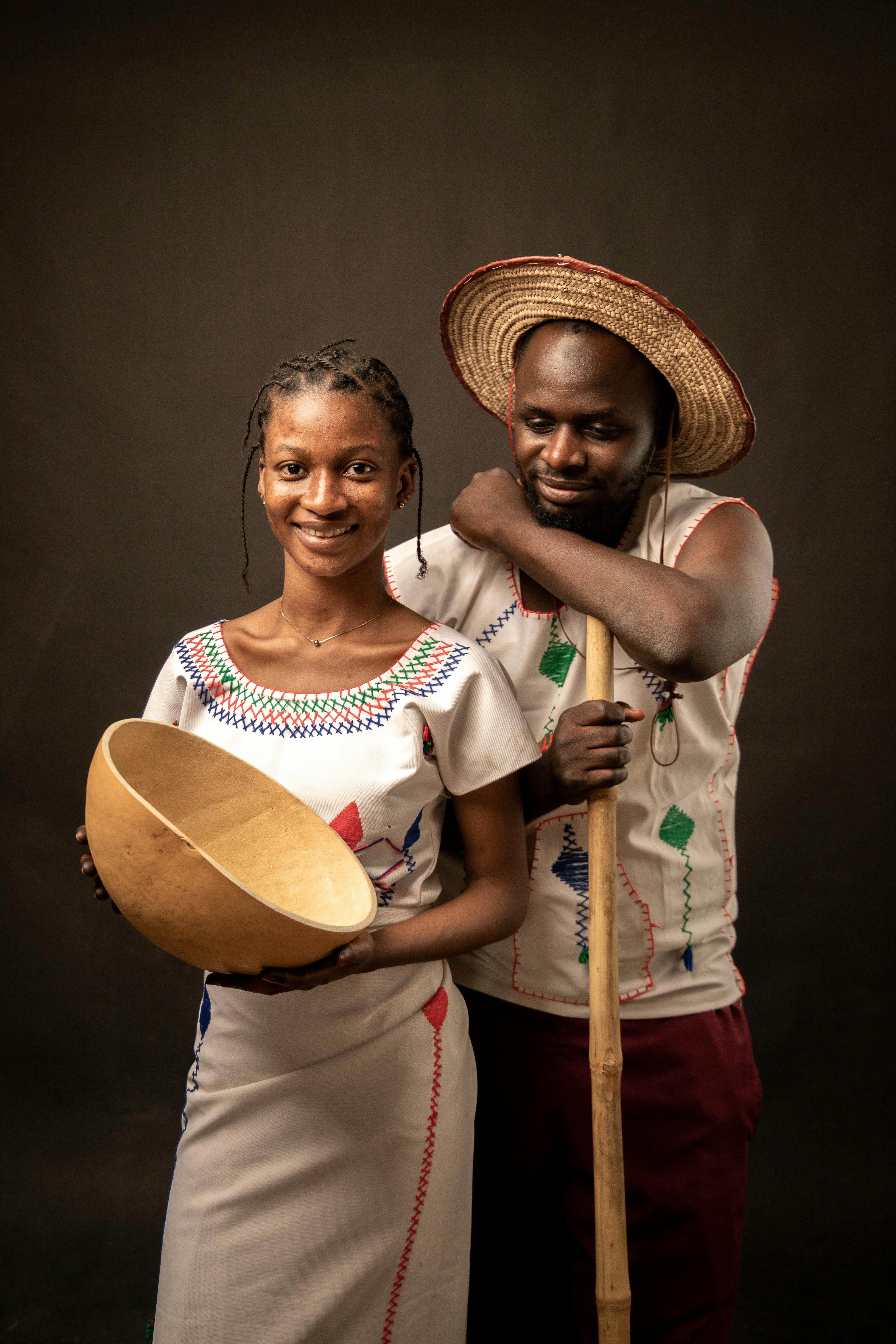 Portrait of a Nigerian couple in traditional attire holding a wooden bowl, showcasing cultural heritage.