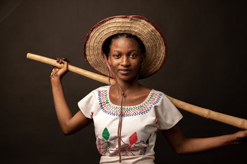 A woman in a straw hat holding a wooden stick