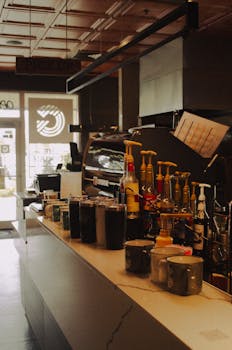 Warm coffee shop interior featuring an inviting beverage counter with various drinks and condiments.