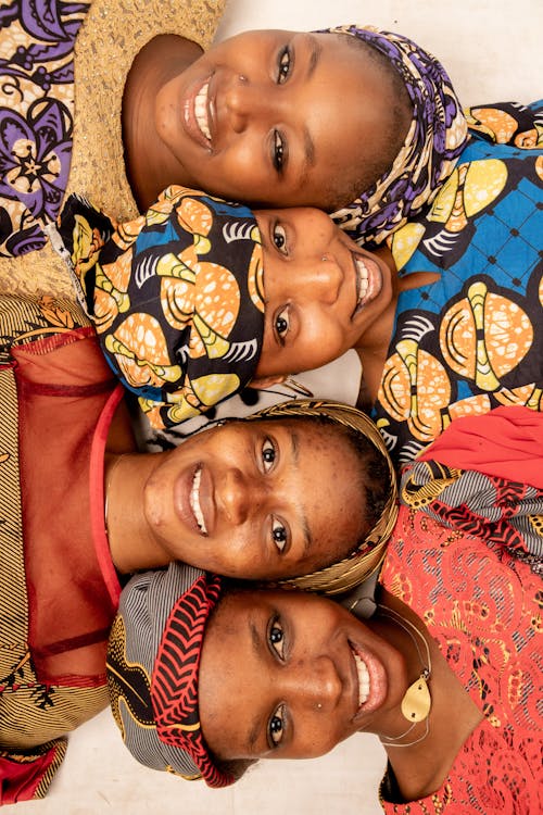 Four women in colorful headscarves are smiling