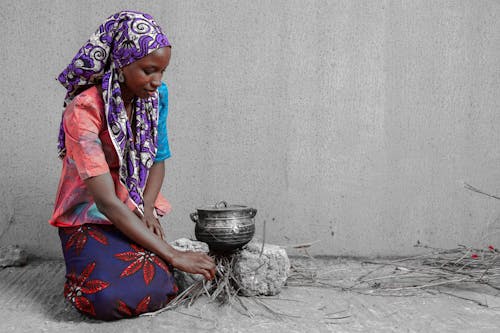 A woman is kneeling down and pouring water into a pot