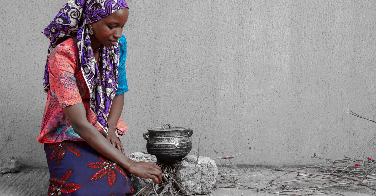 A local Ewe woman cooking akple over an open fire in a village