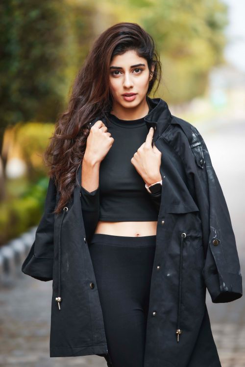 Free Fashionable woman with a black coat and crop top posing outdoors. Stock Photo