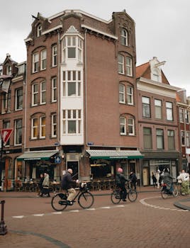 Urban scene with cyclists in Amsterdam, showcasing historic townhouses and vibrant city life.