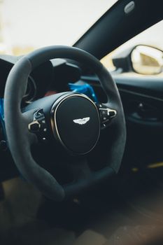 Close-up of a sleek Aston Martin steering wheel showcasing luxury car interior design.