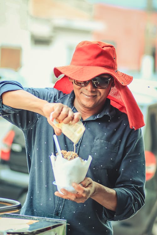 Free Man Pouring Sauce on Bowl of Street Food Stock Photo