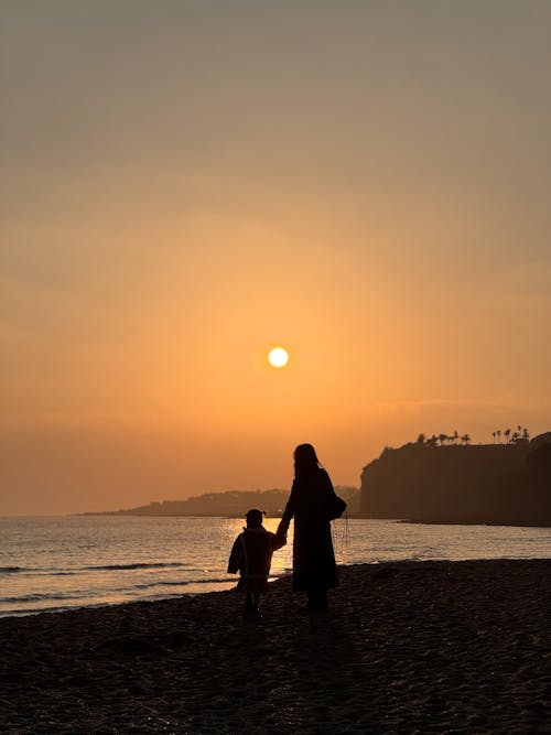 A Woman with a Child on the Beach at Sunset