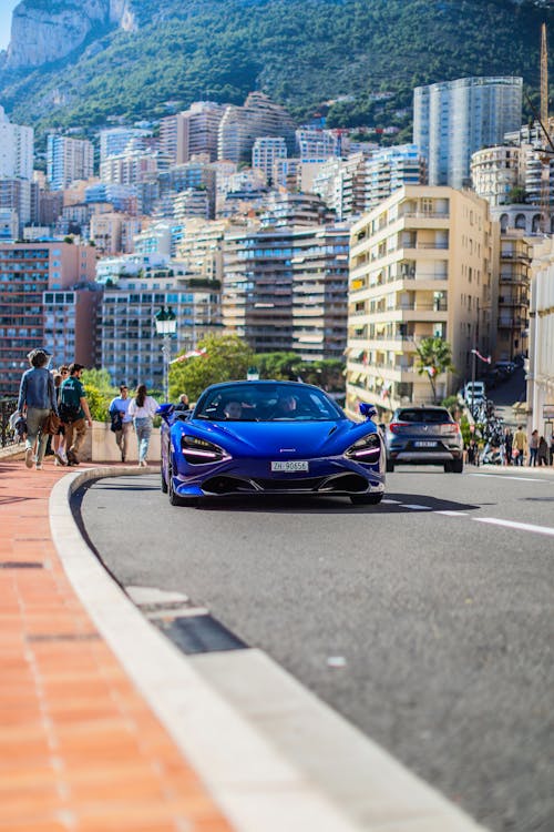 A blue sports car driving down a city street