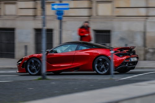 A red sports car driving down the street