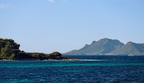 Free A serene coastal landscape featuring lush greenery and a majestic mountain under a clear sky. Stock Photo