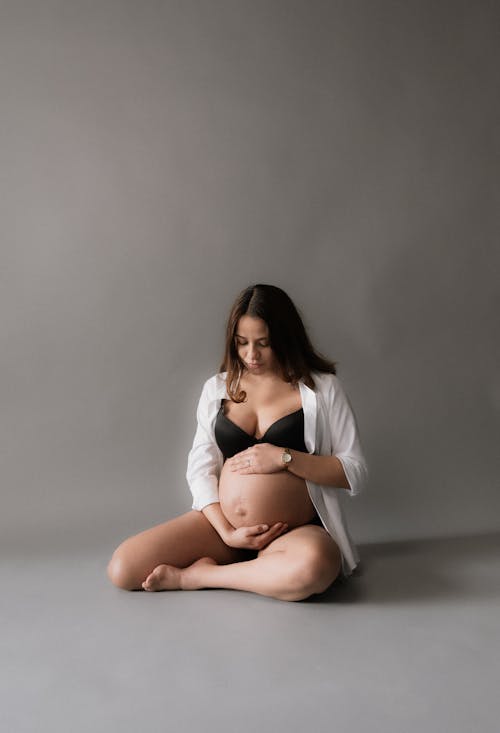 A pregnant woman in a white bra and underwear