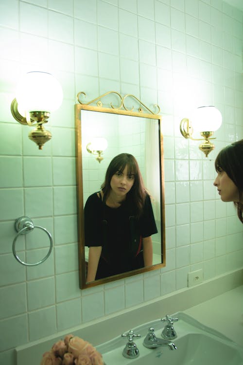 Free Woman in Black T-shirt Staring on Wall Mirror Stock Photo