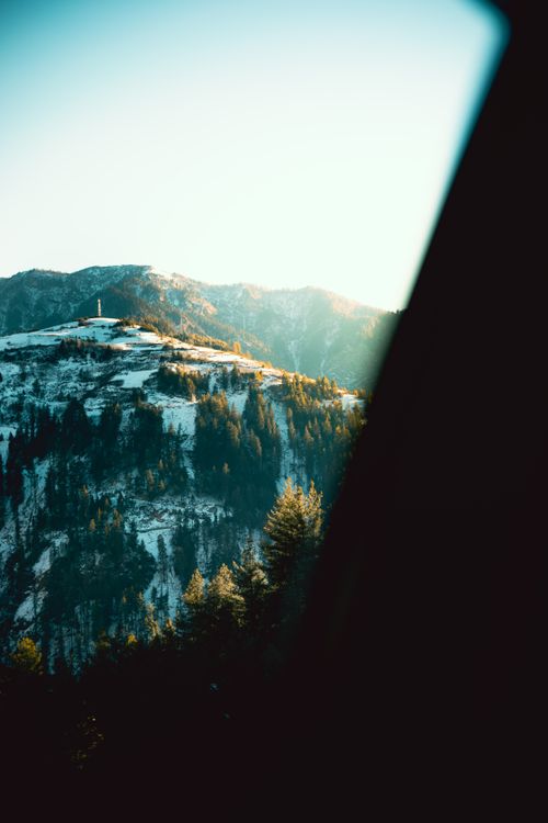 Free Breathtaking winter mountain view with snow-covered peaks and evergreen trees at sunset. Stock Photo