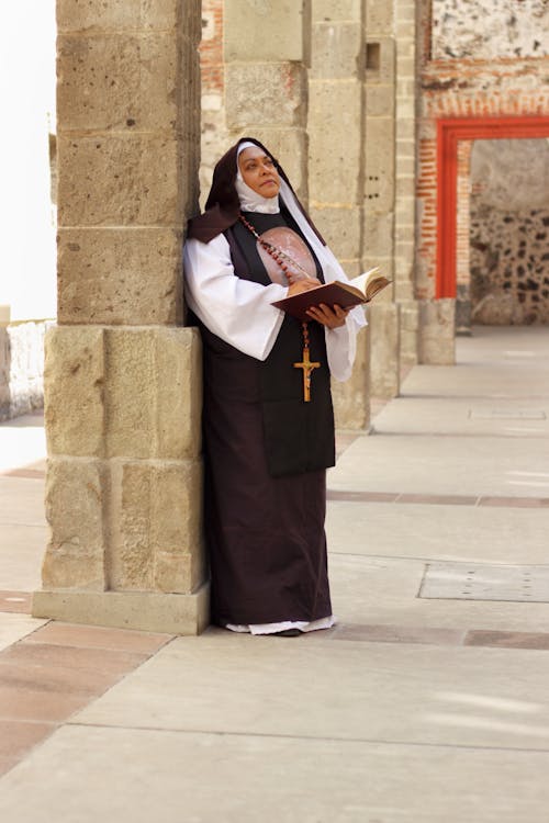 A nun standing on a stone pillar holding a book