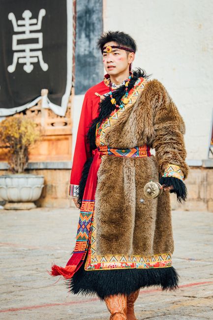 Portrait of a man in traditional fur coat outdoors, showcasing vibrant ethnic attire.