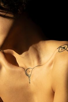 A close-up view of minimalist line tattoos on human skin under warm sunlight.