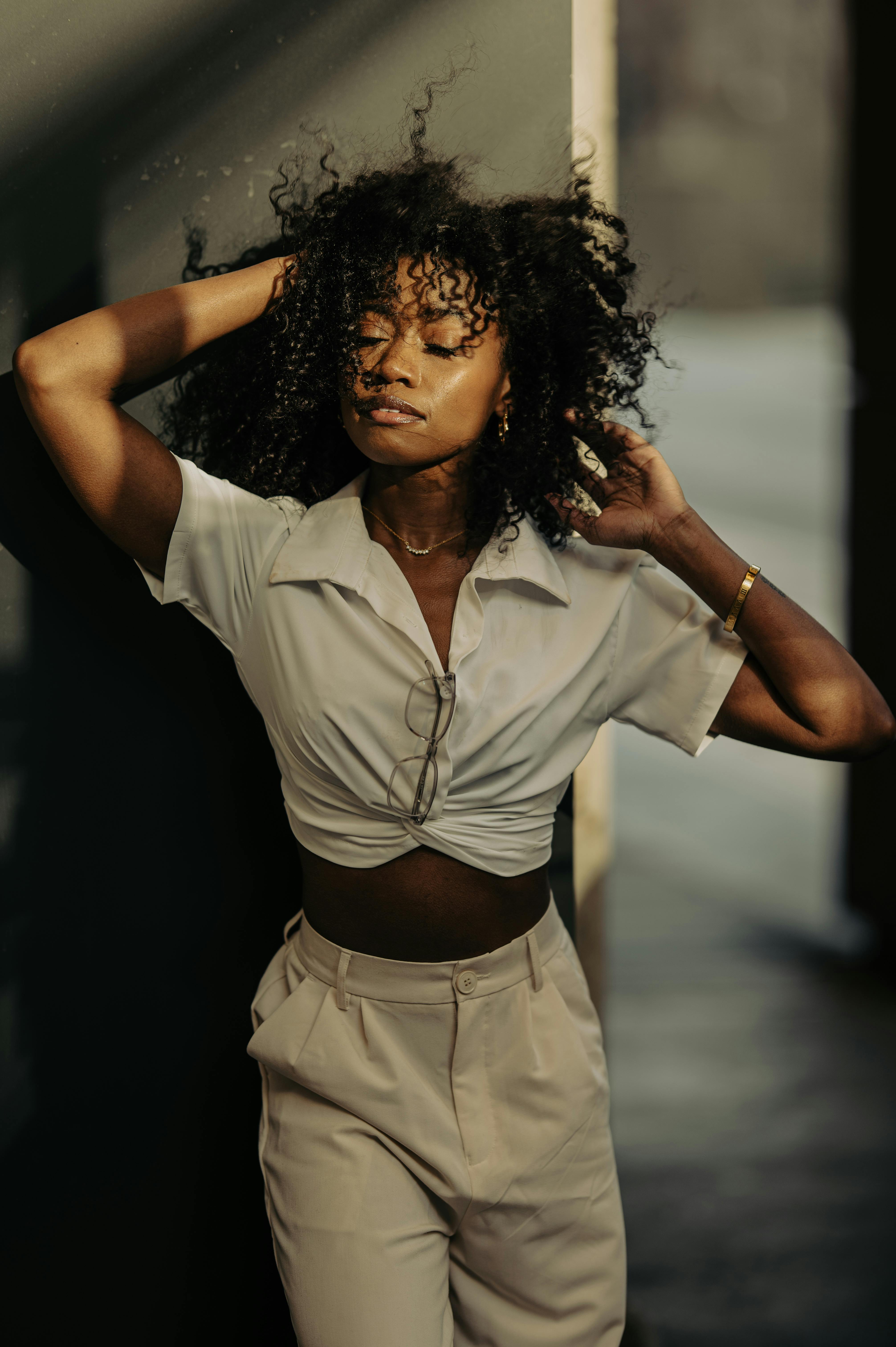 Fashionable woman with afro hairstyle posing in sunlit outdoor setting in Atlanta.
