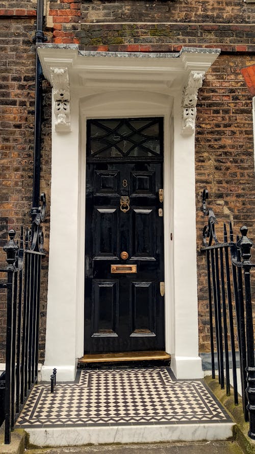 A black door with a tiled floor and a black iron gate