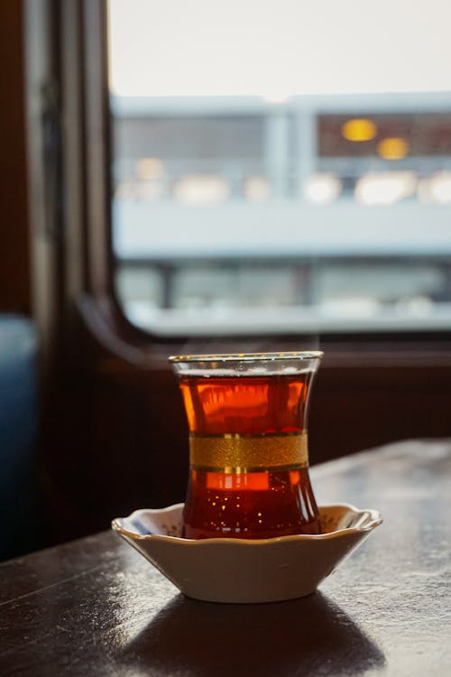A cup of tea sits on a table in front of a window