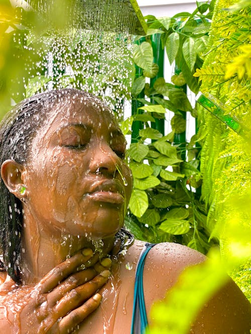 A woman is taking a shower in a garden