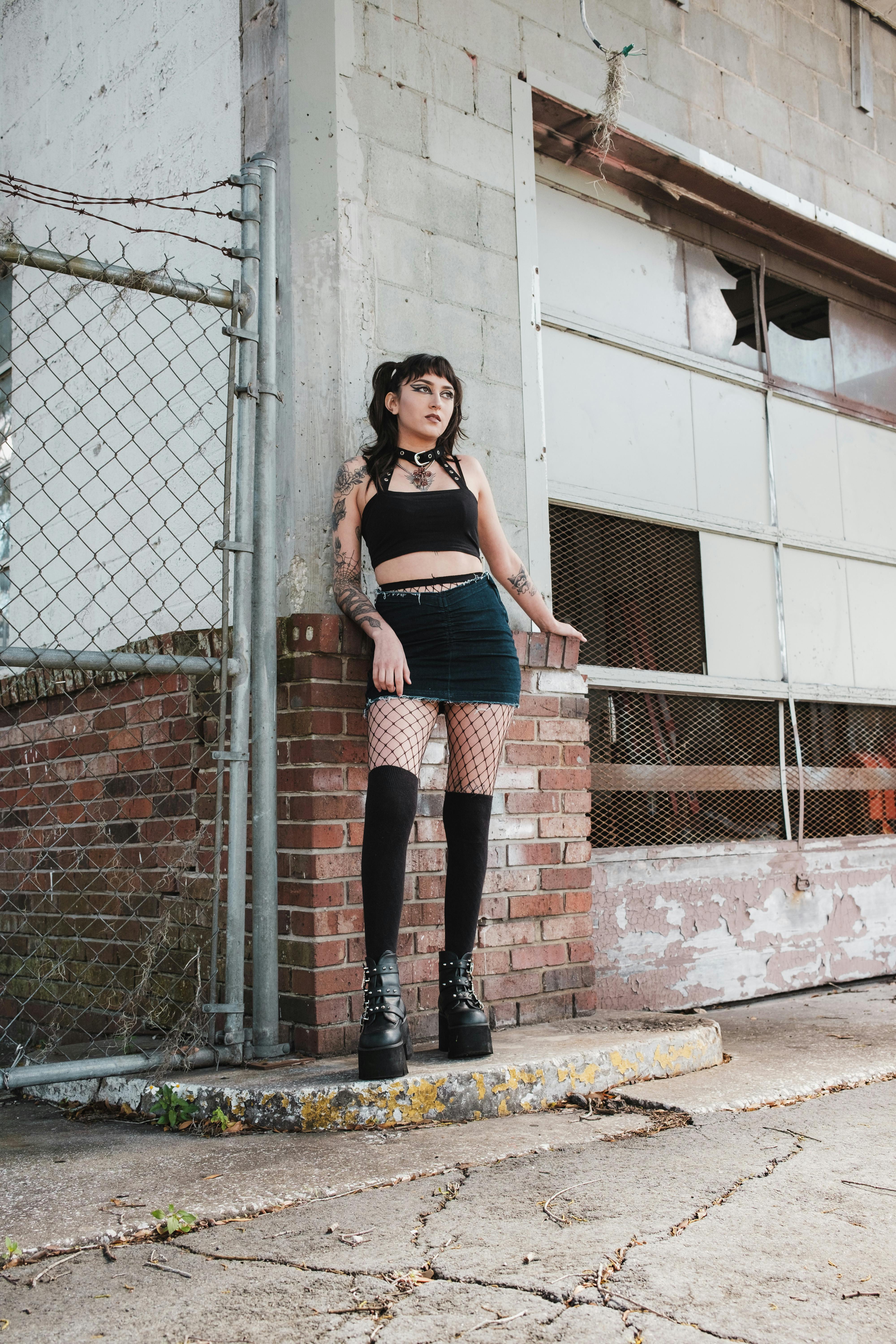 woman in fishnet tights stands by wall