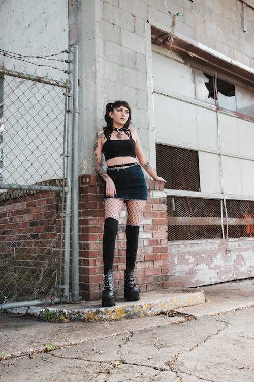 Woman in Fishnet Tights Stands by Wall