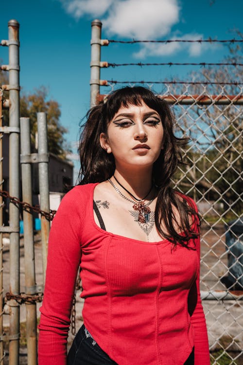 A woman with tattoos standing in front of a fence