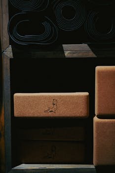 Neatly organized cork yoga blocks and rolled mats on a wooden shelf.