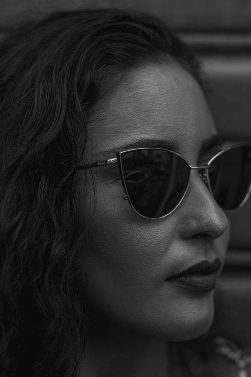Free Artistic black and white portrait of a woman wearing sunglasses with a thoughtful expression. Stock Photo
