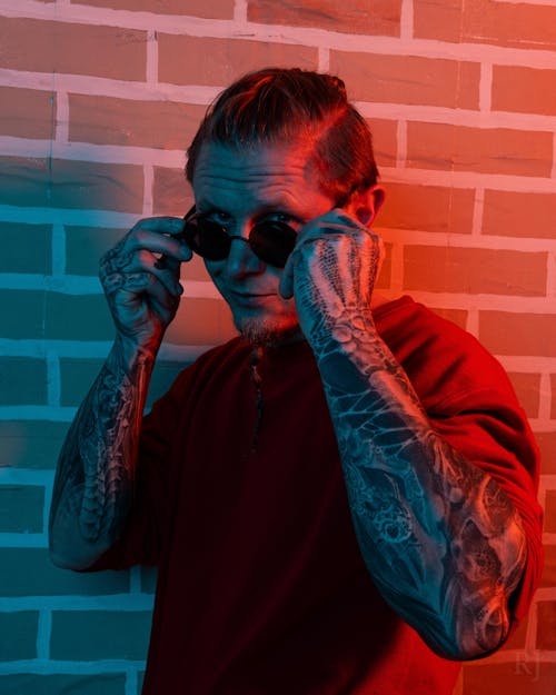 A man with tattoos and sunglasses on his face