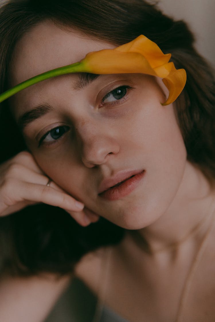 Portrait Of Brunette Woman With Orange Flower 