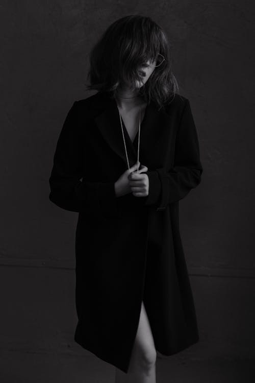 A woman in a coat and heels posing for a black and white photo