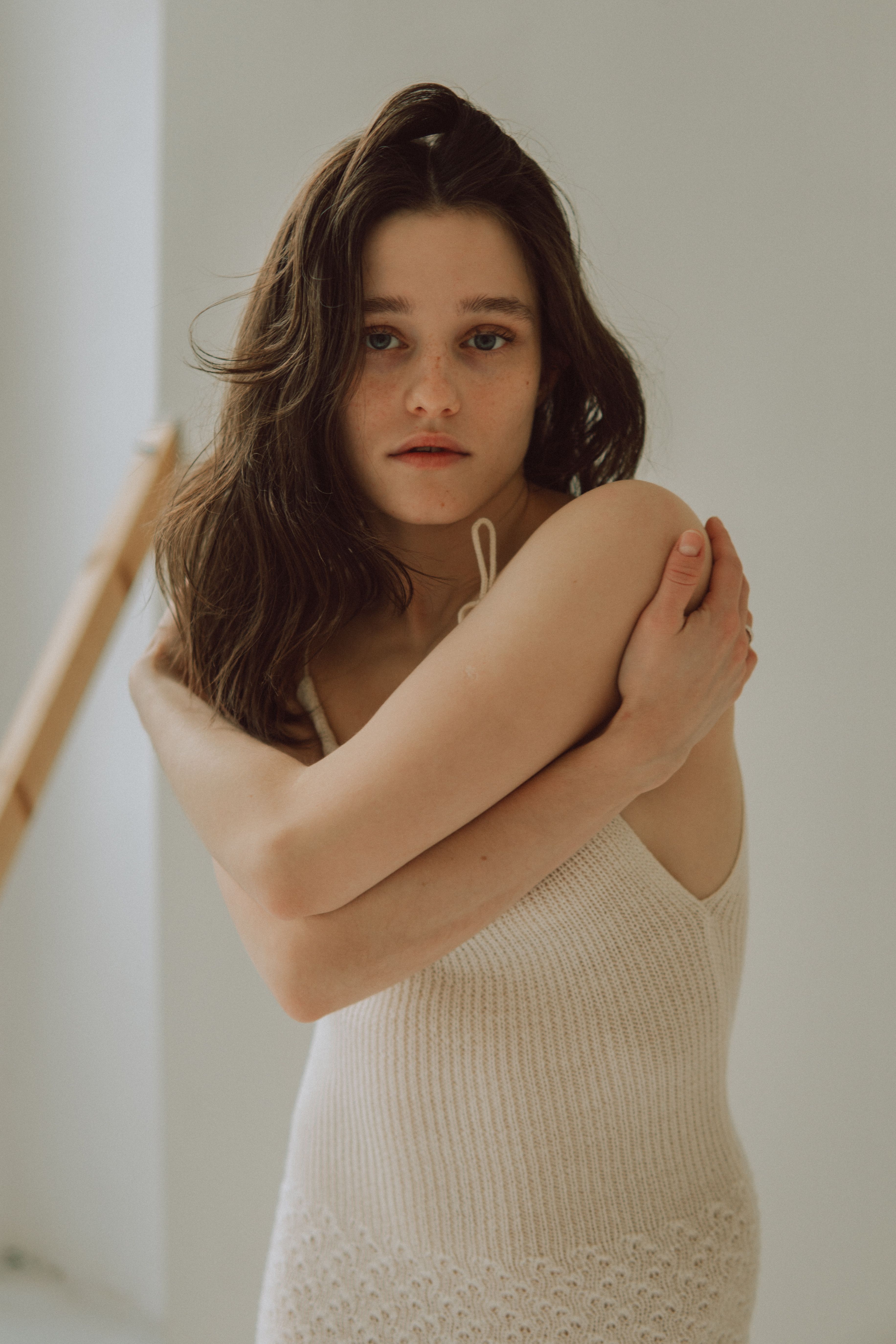 Portrait of a woman embracing herself in a soft, natural setting.