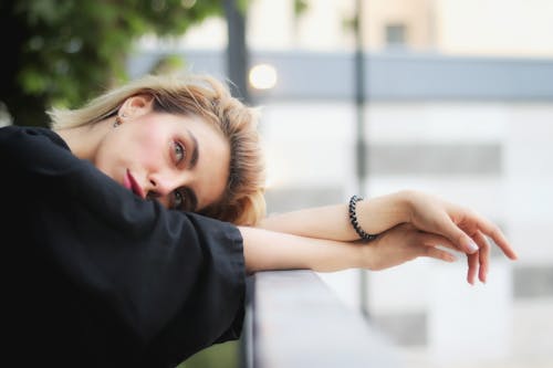 A woman leaning against a railing with her hand on her chin