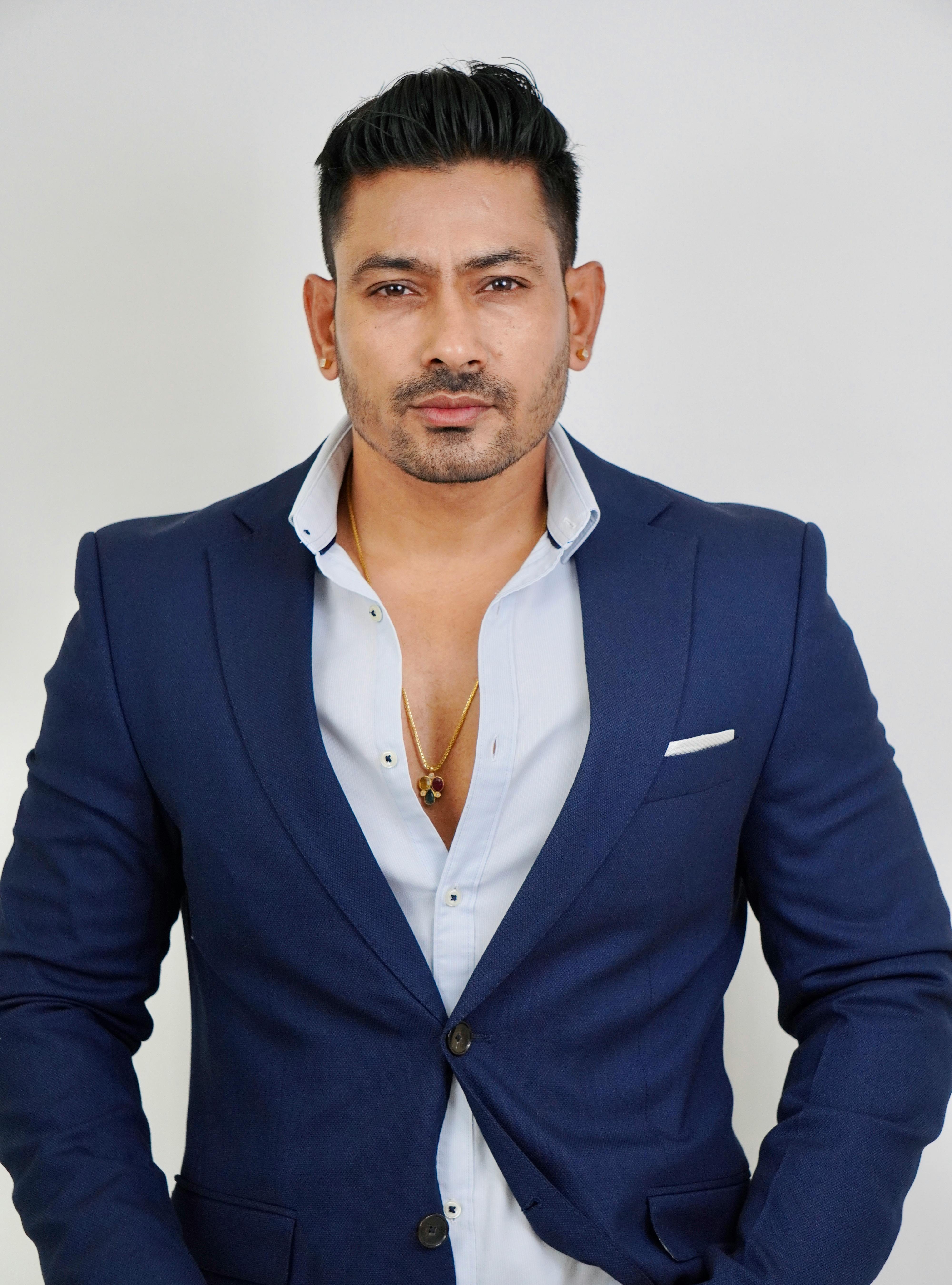 Portrait of a confident man in a blue suit with a white shirt on a clean white background.