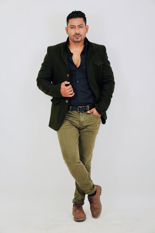 A man in a green blazer and brown pants