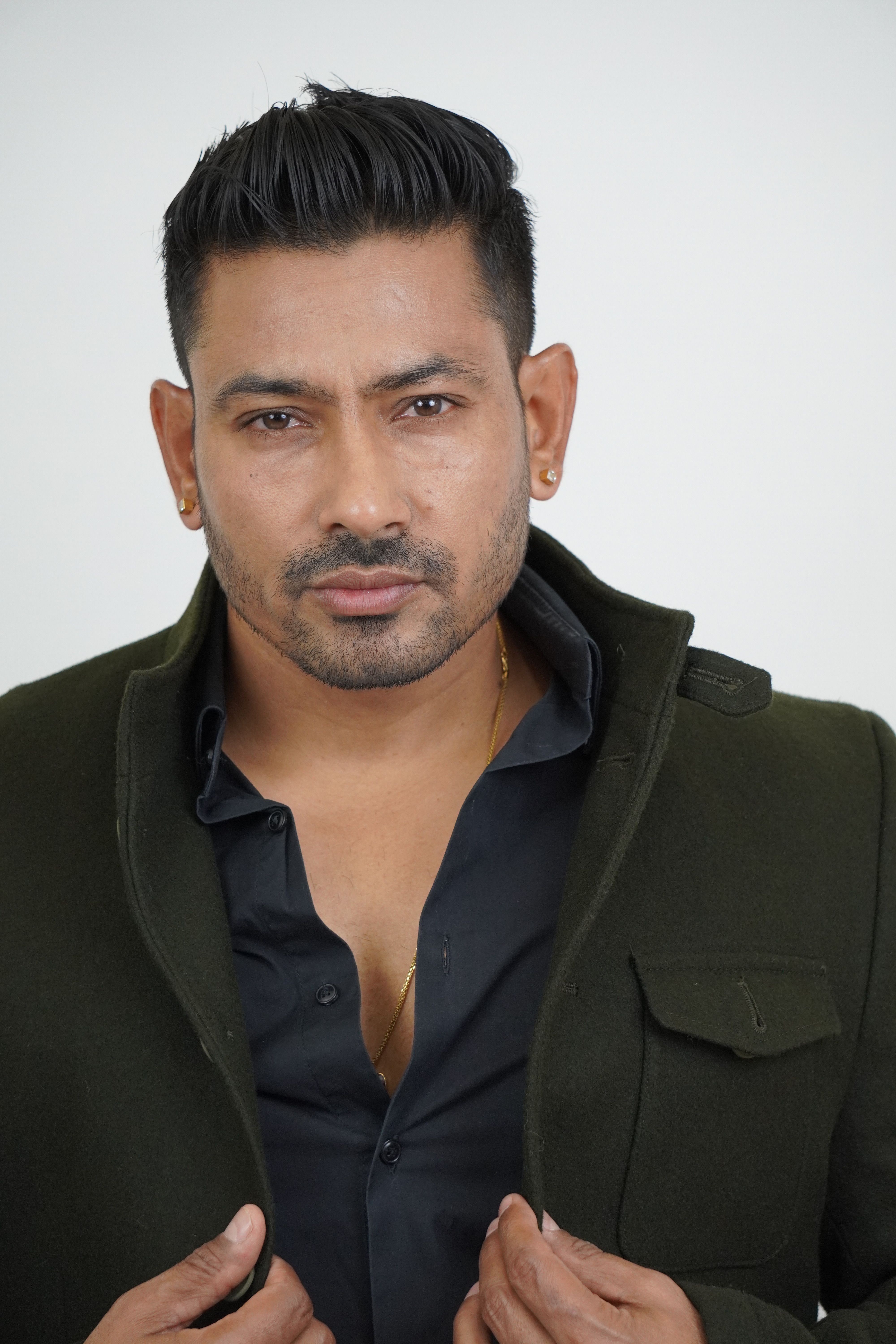 Portrait of a confident man in a dark green jacket with white background.