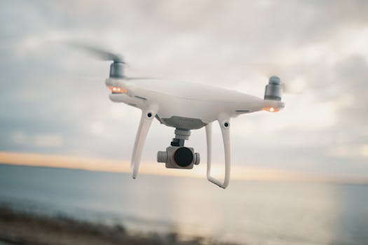 A white drone hovering over a calm ocean at sunset, capturing stunning aerial views.