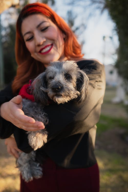 Smiling Redhead Woman Standing and Holding Pet Dog