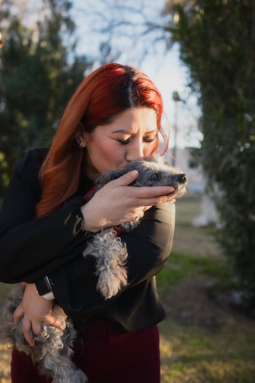 A woman with red hair holding a small dog