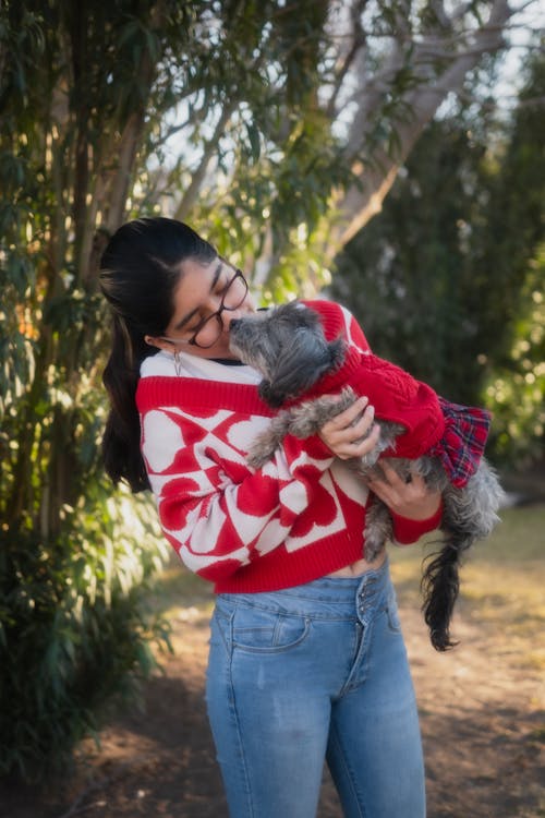 A woman in a red sweater holding a dog