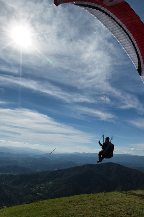 A person paragliding over a mountain with a blue sky