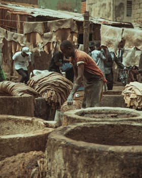 A man working in a rural tannery, showcasing traditional leather processing methods.