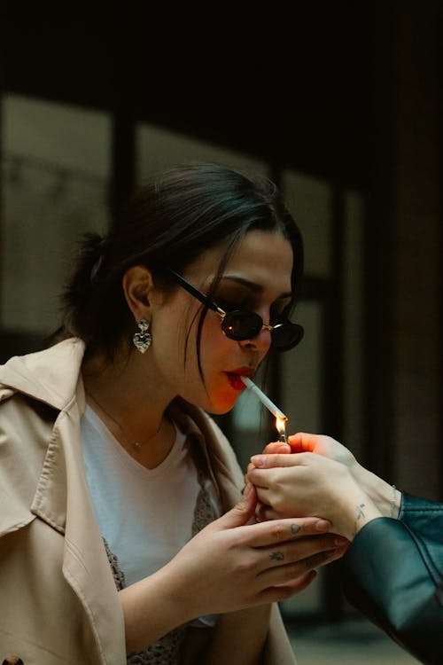 A woman smoking a cigarette with sunglasses on