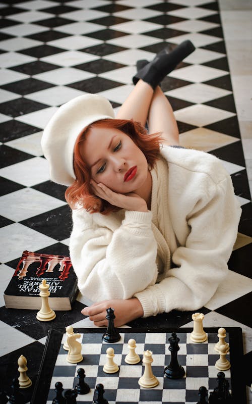 A woman laying on the floor playing chess