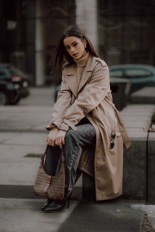 A woman in a trench coat sitting on a bench