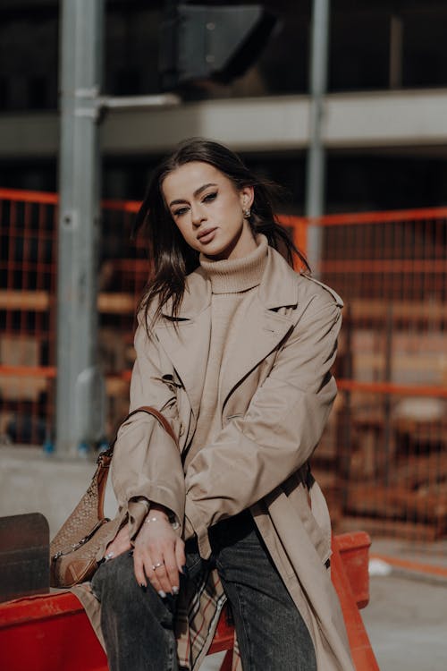 A woman in a trench coat sitting on a bench