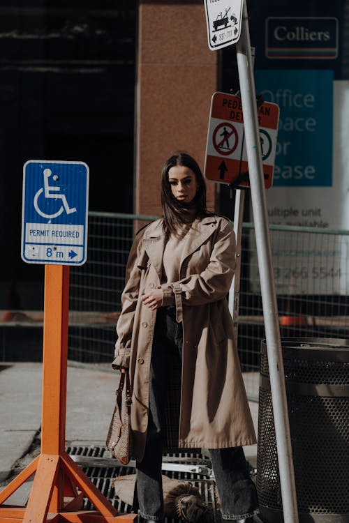 Woman in Trench Coat and Turtleneck Sweater among Street Signs